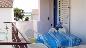 A balcony with a table and chairs, a view of the sea, and a building with a tiled roof. - Apartment in Pakoštane with Seaview, Balcony, Air condition, WIFI (3539-2) (Pakoštane)