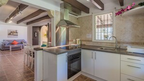 A compact kitchen with a built-in oven, a stainless steel range hood, and a window with bars. - LA RAFAL  ref. VP26 (Pollensa / Pollen��������������������������������������������������������������a)