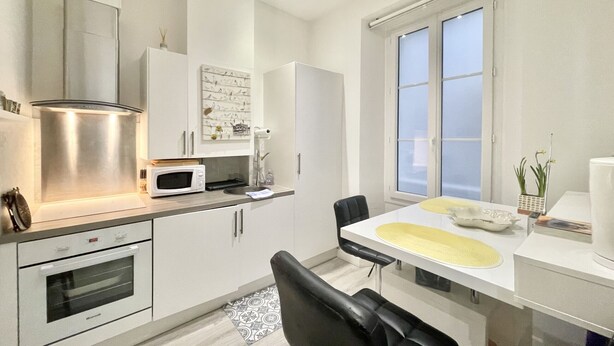 A modern kitchen with white cabinets, a microwave, a stove, and a dining area with a table and chairs.