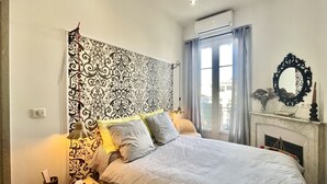 A neatly made bed with a patterned headboard, a bedside lamp, and a small bedside table with a tissue box.
