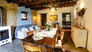 A cozy dining area with a wooden table set for four, a stone wall, and a rustic ceiling.