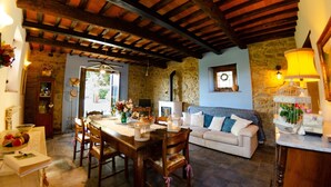 A rustic dining area with a wooden table and chairs, a stone wall, and a cozy blue sofa.