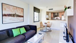 A modern living room with a sofa, coffee table, and a dining area with chairs and a table. - MILENI 3 1 1 4 Roses (Rosas / Roses)