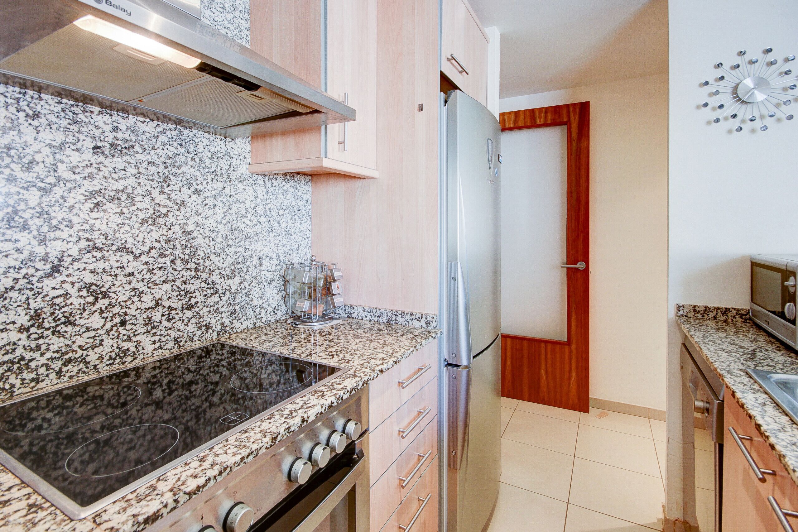 A modern kitchen with granite countertops, stainless steel appliances, and wooden cabinets.