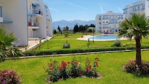 Un hôtel moderne doté d’une piscine, de jardins bien entretenus et offrant une vue dégagée sur les montagnes en arrière-plan.