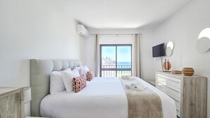 Ein modernes Schlafzimmer mit einem großen Bett, einem Flachbildfernseher und einem Balkon mit Meerblick.