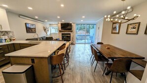 Una cocina moderna con una isla central, taburetes de bar y una mesa de comedor con sillas.