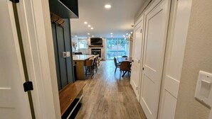 Un pasillo que conduce a un comedor con cocina y un televisor montado en la pared.