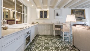 A kitchen with white cabinets, a dining area with a table and chairs, and a patterned floor. - Ca' Dell'Ulivo (Venice)