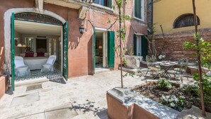 A courtyard with outdoor seating, a small garden, and a building entrance with a door and windows. - Ca' Dell'Ulivo (Venice)