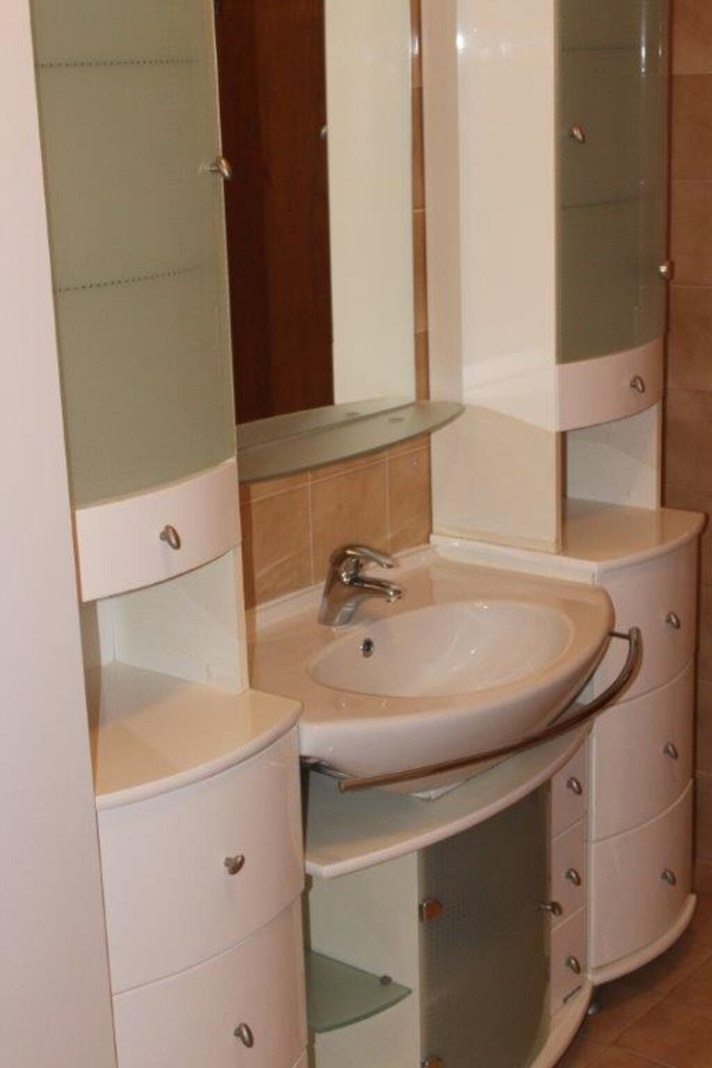 A bathroom with a round sink, a mirror, and a cabinet with drawers.