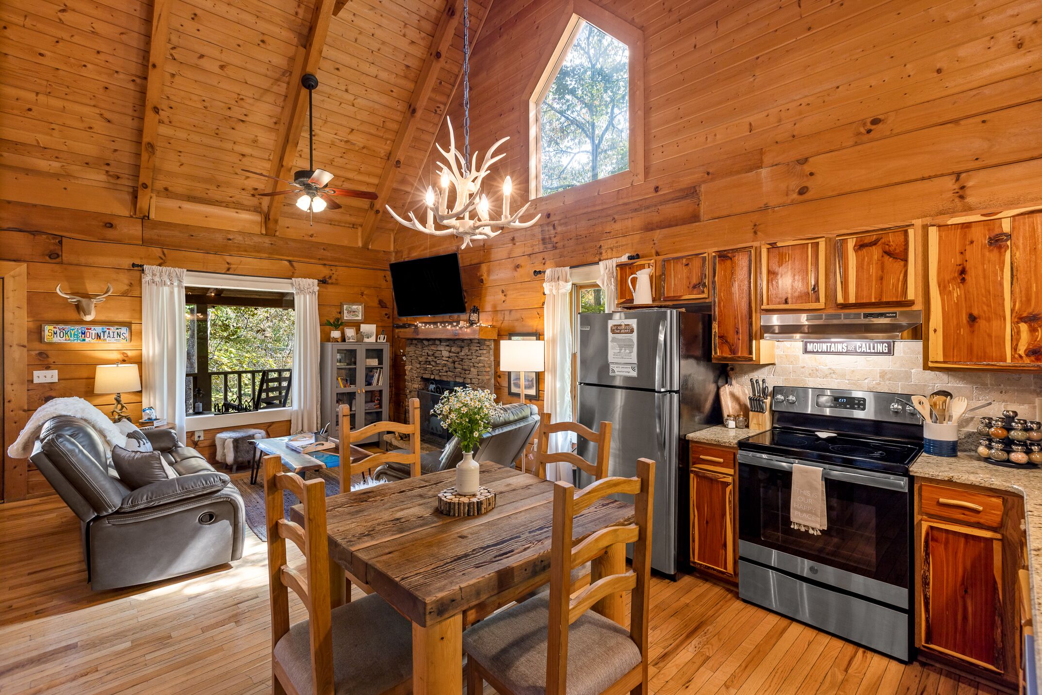 Un intérieur de chalet chaleureux comprenant un coin repas, une cuisine et une cheminée.