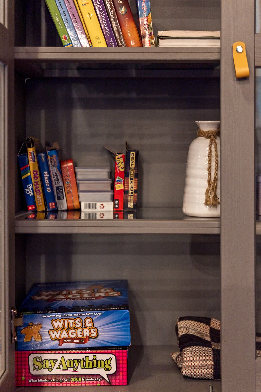 Une bibliothèque contenant des livres, des jeux de société et une boîte de jeux.