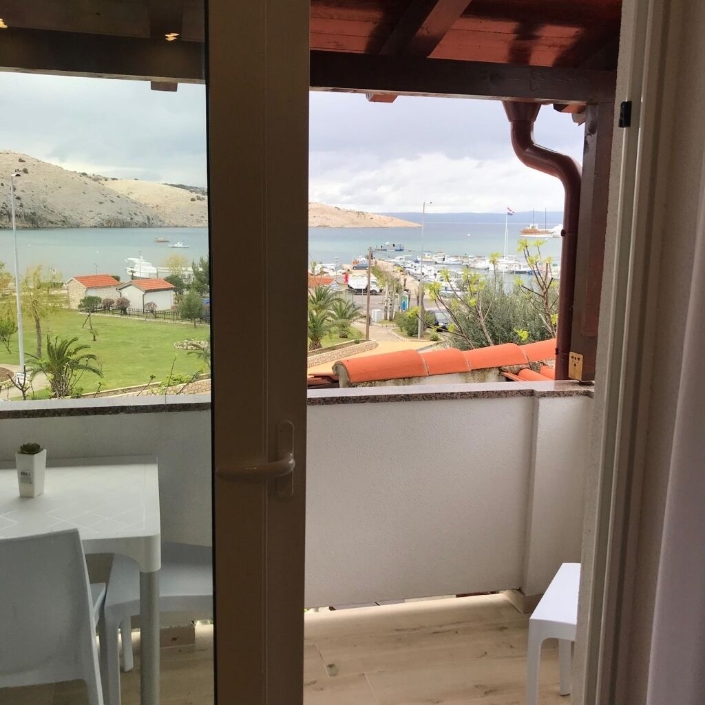Ein Balkon mit Blick auf eine Küstenlandschaft, einschließlich eines Sandstrandes und eines Yachthafens.