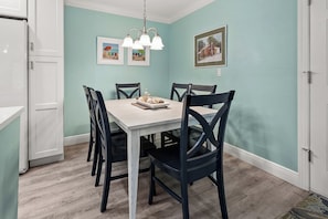 Un espace repas comprenant une table, des chaises et des œuvres d’art accrochées aux murs.