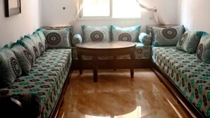 A cozy living room with a round wooden coffee table, patterned sofas, and a large window with curtains. - Beautiful apartment in Essaouira 4158 (Essaouira)