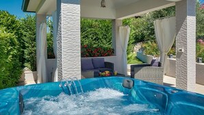 A hot tub with a stone wall backdrop, a cushioned seating area, and a clear view of lush greenery. - Holiday Home in Ripenda Kras with Loggia, Air condition, WIFI, Washing machine (676-1) (Ripenda Kras)