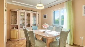 A dining area with a table, chairs, a cabinet, and a window with curtains. - Holiday Home in Ripenda Kras with Loggia, Air condition, WIFI, Washing machine (676-1) (Ripenda Kras)