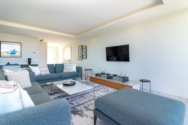 A modern living room with a sofa, coffee table, and a flat-screen TV mounted on the wall.