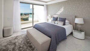 Un dormitorio moderno con una cama grande, un banco, una mesita de noche y vistas al exterior.