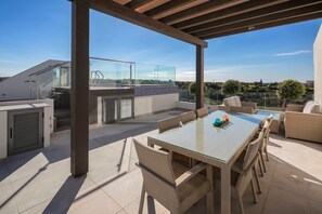 Una terrazza sul tetto con ringhiera in vetro, arredi da esterno e vista sul paesaggio.