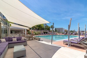 A poolside area with lounge chairs, a bar, and a seating area with a sofa.