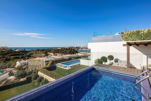 A rooftop swimming pool with a view of the sea and cityscape.