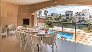 Un balcon avec une table à manger, des chaises et une vue sur une piscine et des immeubles.