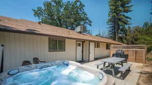 A backyard with a hot tub, patio table, and chairs.