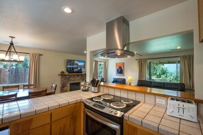 A kitchen with a central island, a stove, a range hood, a built-in oven, and a built-in toaster.
