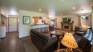 A spacious living room with a fireplace, leather sofas, a coffee table, and a TV.