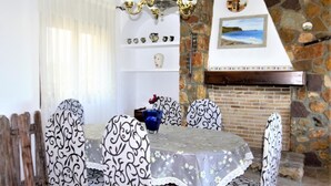 A dining area with a stone fireplace, a chandelier, and patterned tablecloths. - Impala - Javea, Costa Blanca (Javea)