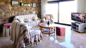 A living room with a stone wall, a sofa, a coffee table, and a TV. - Impala - Javea, Costa Blanca (Javea)