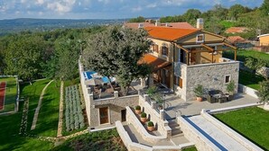 Uma casa grande com fachada de pedra, piscina e um jardim bem cuidado.