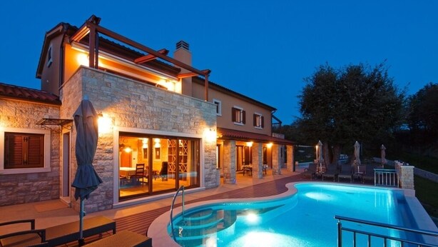 Uma casa moderna com piscina, fachada de pedra e área de estar externa.