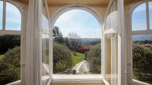 A room with three arched windows overlooking a garden with a white umbrella.