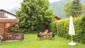 Eine Holzhütte mit Essbereich, einem großen Baum und Bergblick.