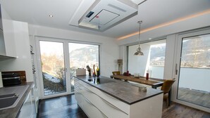 Una cocina moderna con una isla central, ventanas amplias y vistas a las montañas.