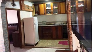 Cocina compacta con armarios de madera, un refrigerador y piso de baldosas.