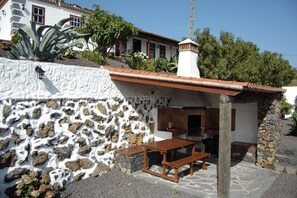 A stone wall, a wooden table, and a small building with a tiled roof.