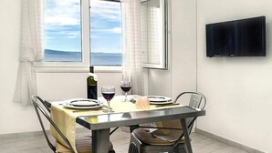 Un coin repas avec une table dressée pour deux personnes, une bouteille de vin et des verres posés sur la table.