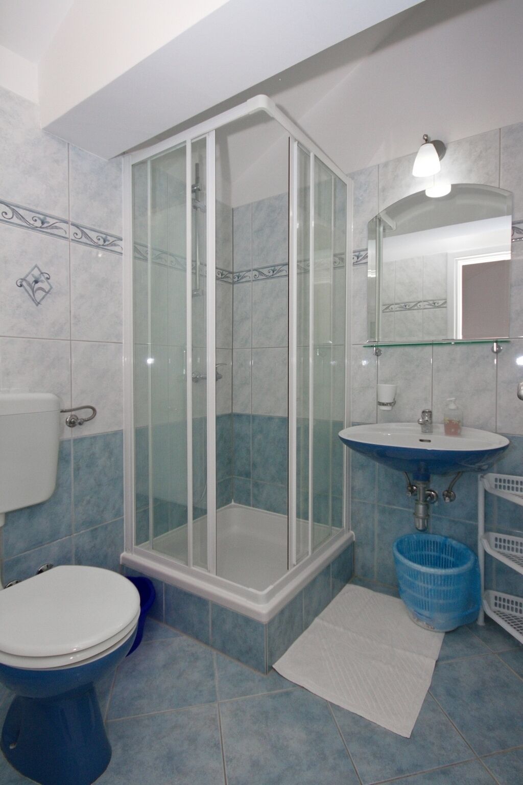 Ein Badezimmer mit Duschkabine, Toilette, Waschbecken und Spiegel.