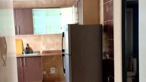 Eine Küche mit dunklen Holzschränken, einem Edelstahlkühlschrank und einer blauen Arbeitsplatte.