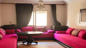 Ein Zimmer mit einem rosa Sofa, einem runden Tisch und einer Chandelier.