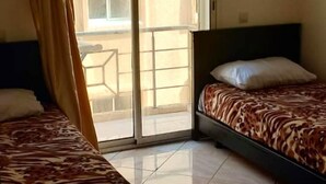 Ein Hotelzimmer mit zwei Betten, einer Schiebetür zum Balkon und einem gefliesten Boden.