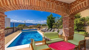 A swimming pool with a view of mountains, surrounded by brick walls and outdoor furniture. - Luxury villa RUSTICA with private pool, jacuzzi and outdoor sauna (Linardići)