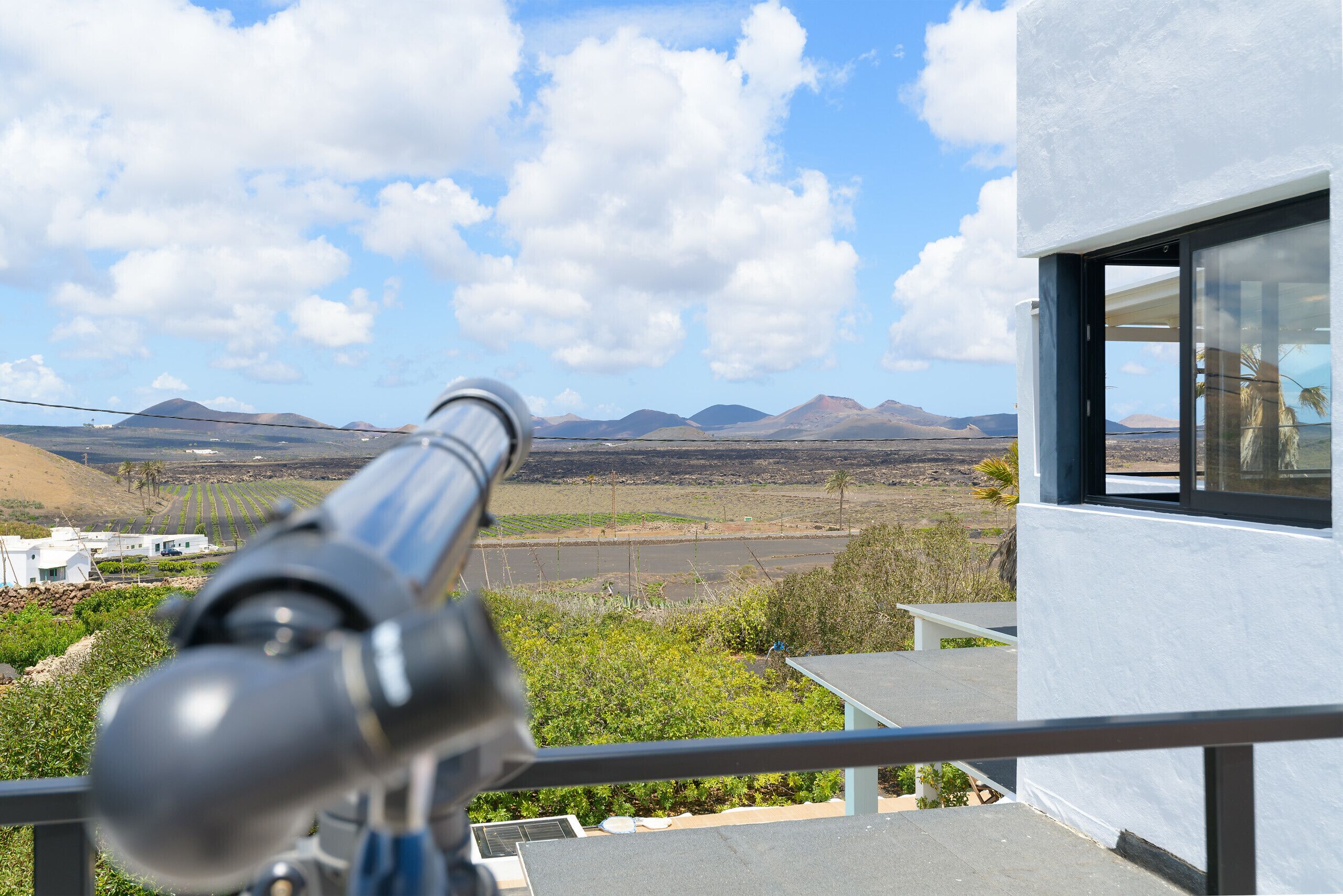 A telescope on a balcony overlooking a mountainous landscape.
