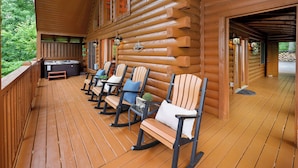 A wooden deck with rocking chairs and a hot tub. - Very Private with Incredible Mountain Views! Free Pool and Putt Putt Access! (Sevierville)
