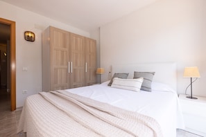 Une chambre à coucher comprenant un lit, des lampes de chevet, une armoire et un luminaire fixé au mur.