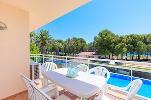 Un balcon avec une table et des chaises, donnant sur une piscine et des arbres.
